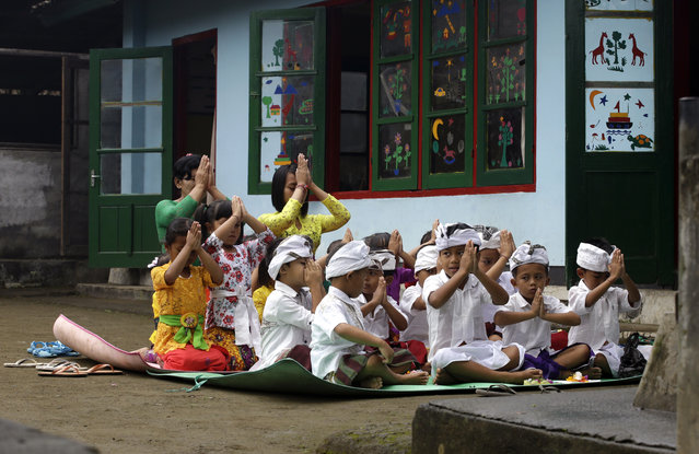 Kindergarten children pray for Mount Agung volcano in their school in Karangasem, Bali, Indonesia, Thursday, October 5, 2017. More than 140,000 people have fled from the surrounds of Mount Agung since authorities raised the volcano's alert status to the highest level on Sept. 22 after a sudden increase in tremors. It last erupted in 1963, killing more than 1,000 people. (Photo by Firdia Lisnawati/AP Photo)