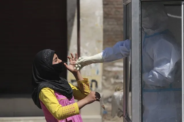 A medical worker takes a nasal swab of a Kashmiri girl at a red zone area in Srinagar, Indian controlled Kashmir, Thursday, April 30, 2020. India says it has achieved tremendous gains and improvement in curbing the coronavirus infections through a stringent lockdown imposed across the country five weeks ago. The government recently allowed reopening of neighborhood shops in cities and towns and resumption of manufacturing and farming activity in rural India to help millions of poor people who lost work. (Photo by Mukhtar Khan/AP Photo)