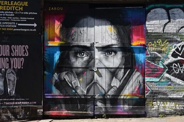 A piece of grafitti of artist BK Foxx wearing her grafitti mask created by French street artist Zabou in East London on April 19, 2020, during the novel coronavirus COVID-19 pandemic. The number of people in Britain who have died in hospital from coronavirus has risen by 596 to 16,060 according to daily health ministry figures on Sunday, April 19. (Photo by Glyn Kirk/AFP Photo)