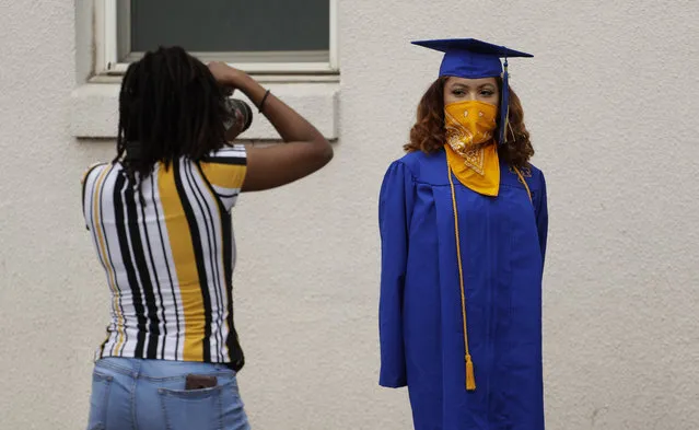 Anderson High School senior Teyaja Jones, right, poses in her cap and gown and a bandana face cover, Tuesday, May 5, 2020, in Austin, Texas. Texas' stay-at-home orders due to the COVID-19 pandemic have expired and Texas Gov. Greg Abbott has eased restrictions on many businesses that have now opened, but school buildings remain closed. (Photo by Eric Gay/AP Photo)