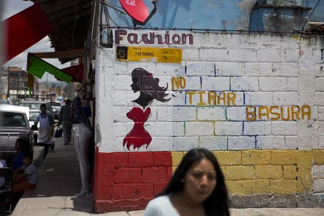 In this August 18, 2017 photo, a woman walks past the wall of a clothing store painted with the figure of a woman as advertising, next to phrase “No dumping garbage”, in Villa Cuauhtemoc, Mexico state. “This problem is difficult to eradicate because it is rooted in ideas that assume that we as women are worth less than men, that we as women can be treated like trash”, said Dilcya Garcia Espinoza de los Monteros, deputy state prosecutor for gender violence crimes, regarding femicides. (Photo by Rebecca Blackwell/AP Photo)