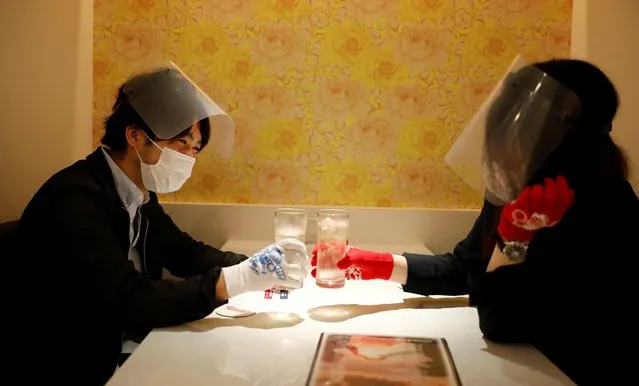 Customers wearing protective masks, face-shields and gloves to prevent infections following the coronavirus disease (COVID-19) outbreak, toast glasses at the cheerleader-themed restaurant “Cheers One” in Tokyo, Japan on May 11, 2020. (Photo by Kim Kyung-Hoon/Reuters)