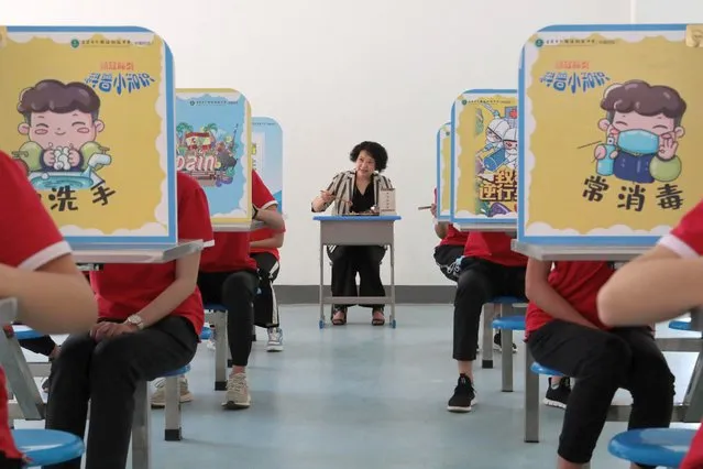 A teacher eats with students at a school where senior middle school students have returned to campus in Yichang, Hubei province, China, May 18, 2020. (Photo by Reuters/China Daily)