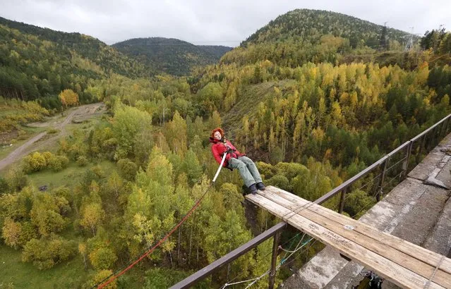 A member of the “Exit Point” amateur rope-jumping group jumps from a 44-metre high (144-ft) waterpipe bridge in the Siberian Taiga area outside Krasnoyarsk, September 13, 2015. (Photo by Ilya Naymushin/Reuters)