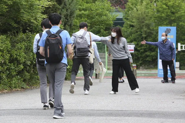 A senior student is greeted by a teacher, second from right, upon his arrival at the Kyungbock High School in Seoul, South Korea, Wednesday, May 20, 2020. South Korean high schools reopened on Wednesday after weeks of postponement due to safety concerns over the coronavirus outbreak. (Photo by Ahn Young-joon/AP Photo)