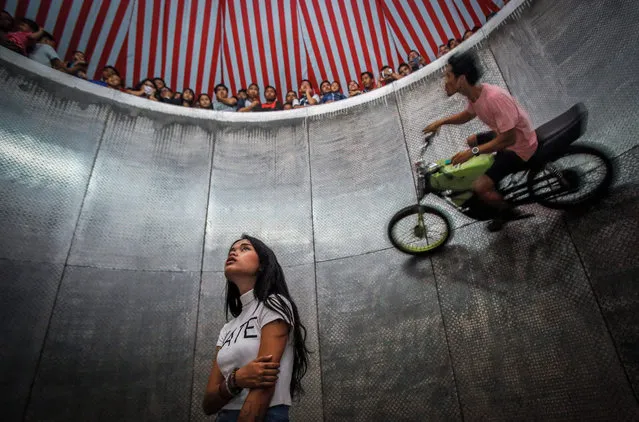 A picture made available on 16 August 2016 shows a young dare devil motorbike rider, Karmila Purba (C), 18, waiting for her turn as other rider perform inside a barrel locally known as “Tong Setan” or Davil's Barrel, at a traditional night carnival in Deliserdang, North Sumatra, Indonesia, 13 August 2016. (Photo by Dedi Sinuhaji/EPA)