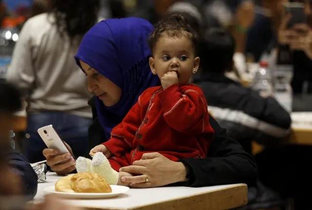 A migrant woman from Syria checks her mobile device as she eats with her daughter at a recetion centre after their arrival at the main railway station in Dortmund, Germany September 13, 2015. (Photo by Ina Fassbender/Reuters)