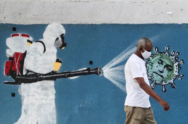 A man walks next to a graffiti depciting a cleaner wearing protective gear spraying viruses with the face of Brazil's President Jair Bolsonaro amid the coronavirus disease (COVID-19) outbreak, in Rio de Janeiro, Brazil, June 12, 2020. (Photo by Sergio Moraes/Reuters)