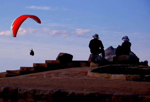 People watch as a paraglider flies past them as they sit atop Long Reef Point on the first day of Spring in Sydney, Australia September 1, 2016. (Photo by David Gray/Reuters)
