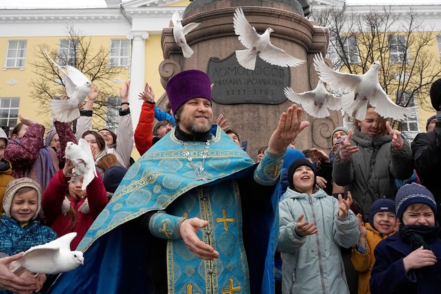 Orthodox priest Father Igor, center, with children and their parents, releases birds celebrating the Annunciation preceding the celebration of Orthodox Easter, in front of the St. Tatiana Church near the Kremlin, in Moscow, Russia, on Monday, April 7, 2025. (Photo by Alexander Zemlianichenko/AP Photo)