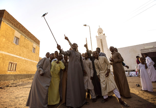 Nubian men and boys take a selfie as they celebrate Eid al Adha, the second and the biggest Eid in the Islamic calendar, in Abo Hour village, Nuba region, Aswan, Thursday, September 24, 2015. Nubians are the inhabitants of the Nuba region which used to extend from the far south of Egypt till the North and the Northwest of Sudan. (Photo by Belal Darder)/AP Photo)