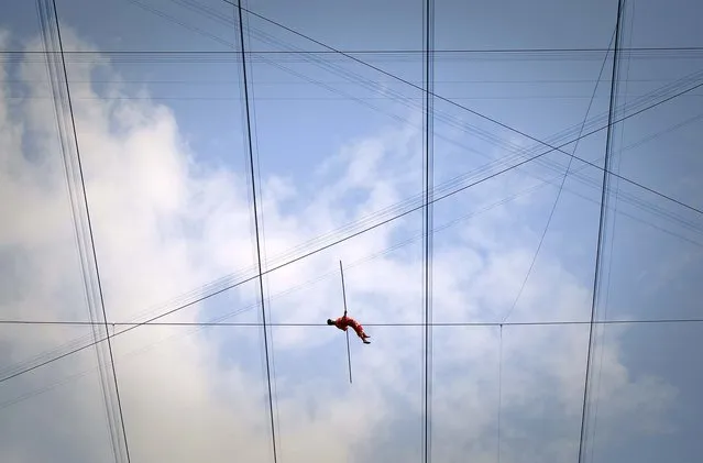 Adili Wuxor lies on a tightrope during the last day of his two-month tightrope walking performance on top of China's National Stadium, also known as the Bird's Nest, in Beijing, Friday, July 2, 2010. Adili, an Uighur ethnic Dawaz tightrope walking performer, has been walking the tightrope five hours a day on the top of the Bird's Nest over the past 60 days, setting a new Guinness World Record. (Photo by Alexander F. Yuan/Associated Press)