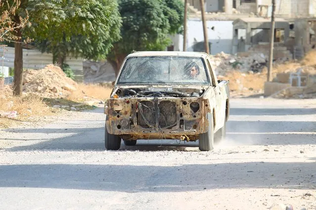 Rebel fighters drive a damaged vehicle in Latamneh city that was hit on Wednesday by Russian air strikes, in the northern countryside of Hama, Syria October 2, 2015. Russian air strikes in northwest Syria which Moscow said targeted Islamic State fighters hit a rebel group supported by Western opponents of President Bashar al-Assad on Wednesday, wounding eight, the group's commander said. (Photo by Ammar Abdullah/Reuters)