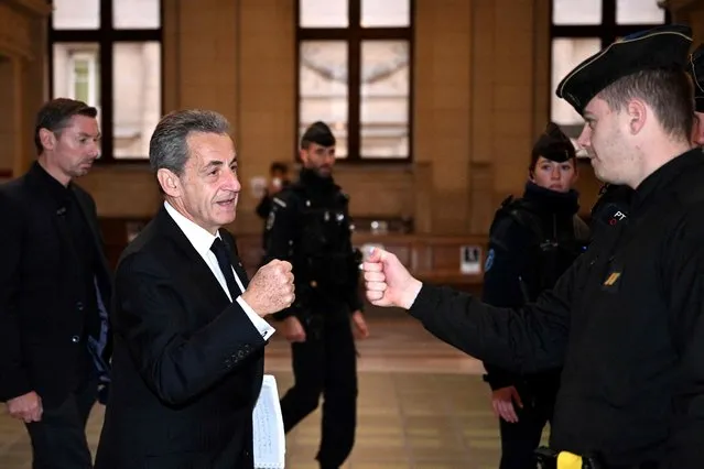 Former French President Nicolas Sarkozy (L) gives a fist bump with a French gendarme as he arrives at the courthouse on the third day of the appeal hearing of a corruption trial at Paris courthouse on December 8, 2022. A French court on March 1, 2021 convicted former President Nicolas Sarkozy on charges of corruption and influence peddling, handing him a three-year prison sentence of which two years are suspended. Prosecutors called for him to be jailed for four years and serve a minimum of two, and asked for the same punishment for his co-defendants – lawyer Thierry Herzog and the judge Gilbert Azibert. (Photo by Emmanuel Dunand/AFP Photo)