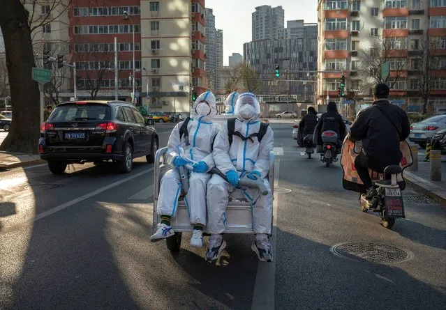 Epidemic control workers wear PPE as they ride on the back of a three wheeler on their way to disinfect an epidemic area on December 9, 2022 in Beijing, China. As part of a 10 point directive, Chinas government announced Wednesday that people with COVID-19 who have mild or no symptoms will be permitted to quarantine at home instead of at a government facility, testings requirements are reduced, people are permitted to buy over the counter medications, and local officials can no longer lock down entire neighbourhoods or cities, a major shift in its zero COVID policy. (Photo by Kevin Frayer/Getty Images)