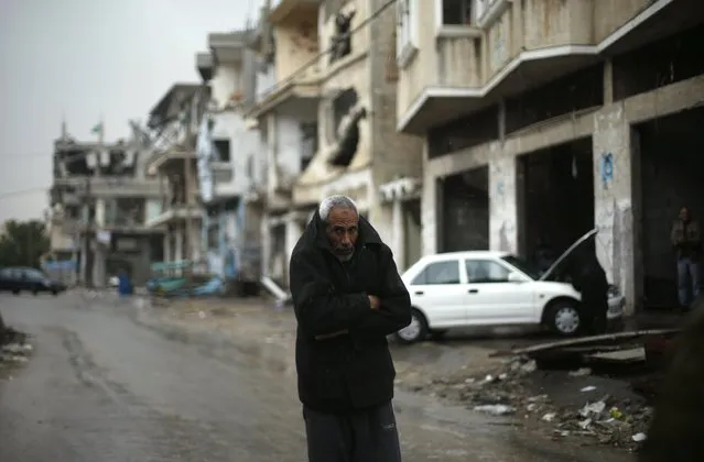 A Palestinian man walks past houses that witnesses said were damaged by Israeli shelling during the most recent conflict between Israel and Hamas, on a rainy day in the east of Gaza City November 16, 2014. (Photo by Suhaib Salem/Reuters)