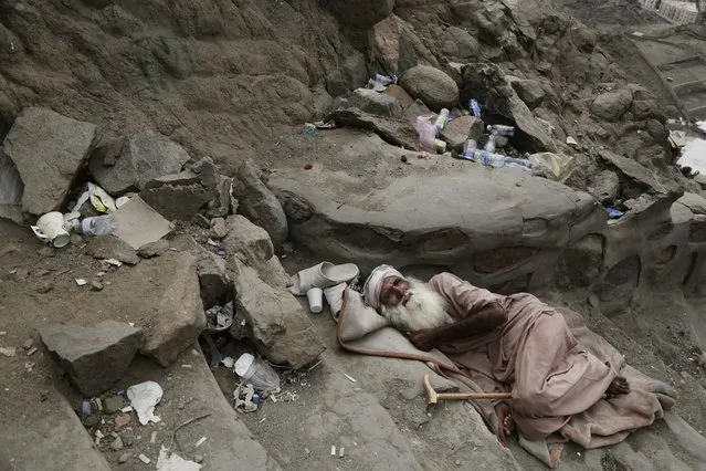 In this Friday, September 9, 2016 photo, a Pakistani man begs on Noor Mountain, where Prophet Muhammad received his first revelation from God to preach Islam, reads before sunrise, on the outskirts of Mecca, Saudi Arabia. Though Hira cave on the mountain remains one of the few sites preserved from the time of the Prophet Muhammad, visitors encounter a markedly different summit than what Muhammad would have experienced. For starters, there are now more than 1,000 steps that guide pilgrims up the rocky hill to the secluded cave. Along the way, entrepreneurial Pakistanis sell bottled water, snacks and tea to pilgrims exhausted by the climb. (Photo by Nariman El-Mofty/AP Photo)