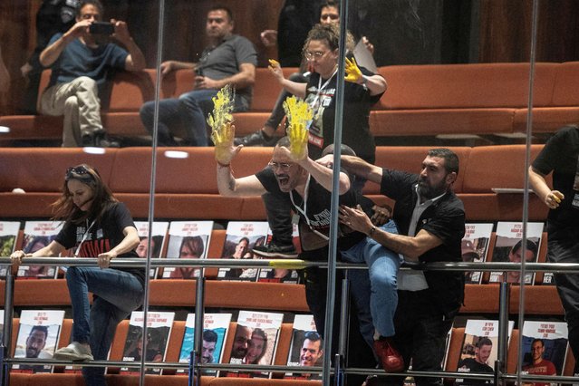 Families and supporters of hostages, kidnapped during the deadly October 7 attack on Israel by Palestinian Islamist group Hamas from Gaza, smear yellow paint, associated with the struggle for the return of hostages, on glass above the plenum as part of a demonstration at the Knesset, Israel's parliament in Jerusalem, on April 3, 2024. (Photo by Oren Ben Hakoon/Reuters)