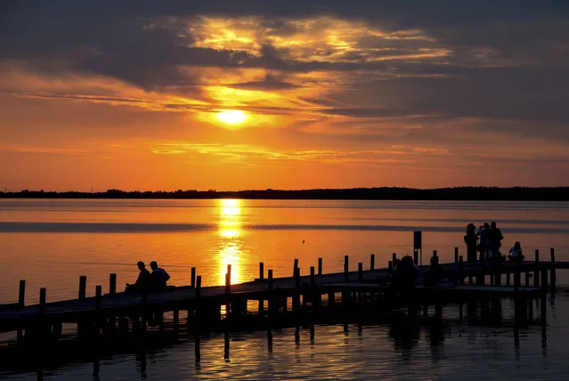 In this photo taken Wednesday, August 16, 2017, people enjoy the sunset at lake Steinhuder Meer near Steinhude, northwestern Germany. (Photo by Hauke-Christian Dittrich/DPA via AP Photo)