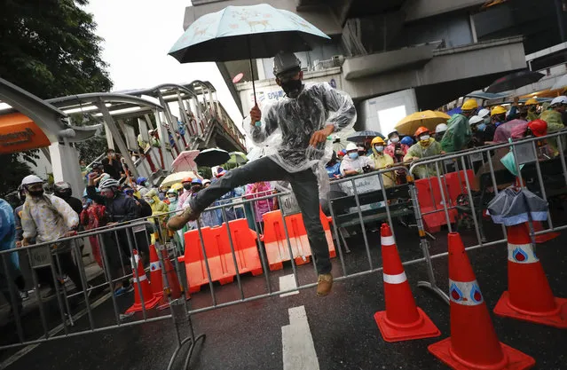 A pro-democracy protester jumps over the barriers during an anti-government protest at Victory Monument during a protest in Bangkok, Thailand, Sunday, October 18, 2020. (Photo by Sakchai Lalit/AP Photo)