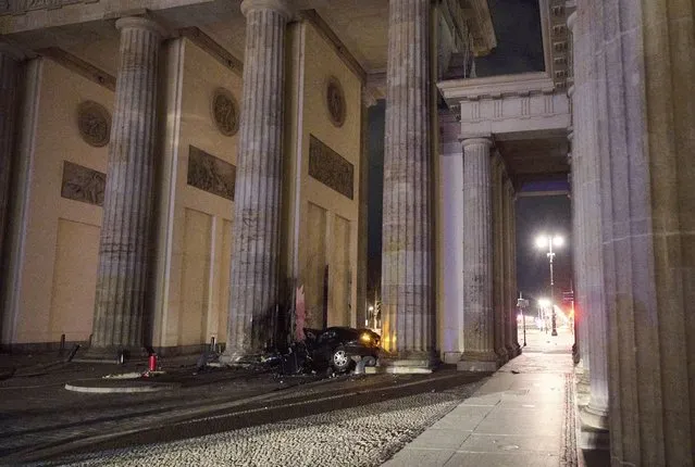 A destroyed car lies between two pillars of the Brandenburg Gate landmark in Berlin, Germany, Monday, January 16, 2023. The car crashed into a pillar of the famous Brandenburg Gate in Berlin. In the car, firefighters found a dead man, said a police spokesman early Monday morning. (Photo by Annette Riedl/dpa via AP Photo)