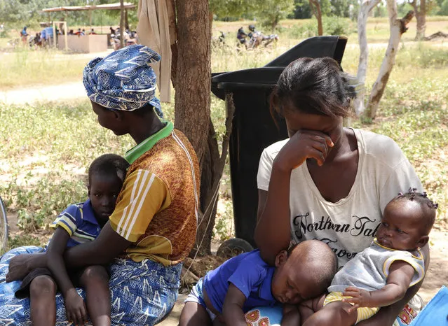 Two women sit outside a small clinic in Gampela village on the outskirts of Burkina Faso's capital, Ouagadougou, Saturday October 10, 2020, waiting to take their children to the doctor. They sometimes wait up to four hours to get medical help. The public health clinic responsible for serving approximately 11,000 people, did not have a working fridge for almost a year. The vaccine cold chain hurdle is just the latest disparity of the pandemic weighted against the poor, who more often live and work in crowded conditions that allow the virus to spread, have little access to medical oxygen vital to COVID-19 treatment, and whose health systems lack labs, supplies or technicians to carry out large-scale testing. (Photo by Sam Mednick/AP Photo)