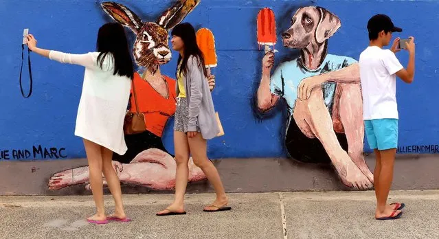 Tourists take photos of street art situated on the promenade at Sydney's iconic Bondi Beach on October 3, 2016. (Photo by William West/AFP Photo)