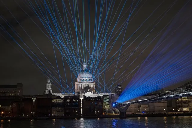 Lights and lasers are displayed to mark the start of the year 2022, after midnight, by the Millennium Bridge going over the River Thames, backdropped by the dome of St Paul's Cathedral in London, Saturday, January 1, 2022. The usual New Year's Eve London firework display by the London Eye ferris wheel was cancelled for the second year running to stop crowds gathering during the UK's current coronavirus outbreak. (Photo by Matt Dunham/AP Photo)