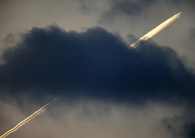 An aircraft flies over Frankfurt, leaving contrails above the cloud early Monday, September 26, 2016. (Photo by Michael Probst/AP Photo)