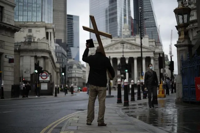 A man holding a cross and a Bible preaches about Christianity backdropped by the Royal Exchange, back center, and the Bank of England, at left, during England's second coronavirus lockdown in the City of London financial district of London, Wednesday, November 18, 2020. Britain yesterday posted 598 COVID-19 deaths of people testing positive for the virus in the last 28 days, the highest daily death toll since May. (Photo by Matt Dunham/AP Photo)