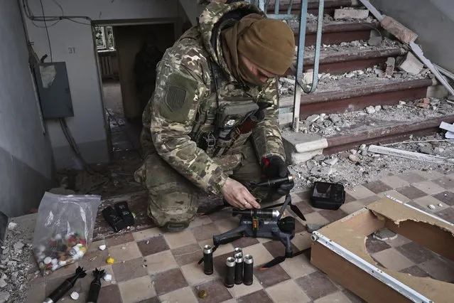 A Ukrainian soldier equips a drone with grenades in the area of the heaviest battles with the Russian invaders in Bakhmut, Donetsk region, Ukraine, Wednesday, March 15, 2023. (Photo by Roman Chop/AP Photo)
