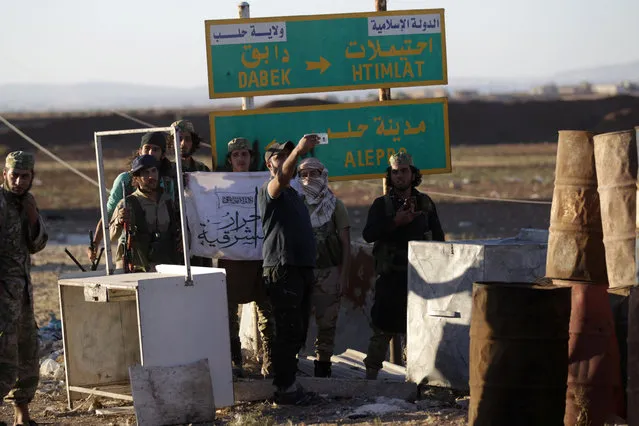 Rebel fighters take a selfie near a road sign in Dabek town, northern Aleppo countryside, Syria October 16, 2016. (Photo by Khalil Ashawi/Reuters)