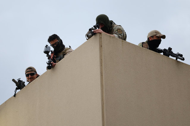 Law enforcement officers, atop U.S. Immigration and Customs Enforcement (ICE) headquarters, point their guns during a protest, in Portland, Oregon, U.S., October 4, 2025. (Photo by Carlos Barria/Reuters)