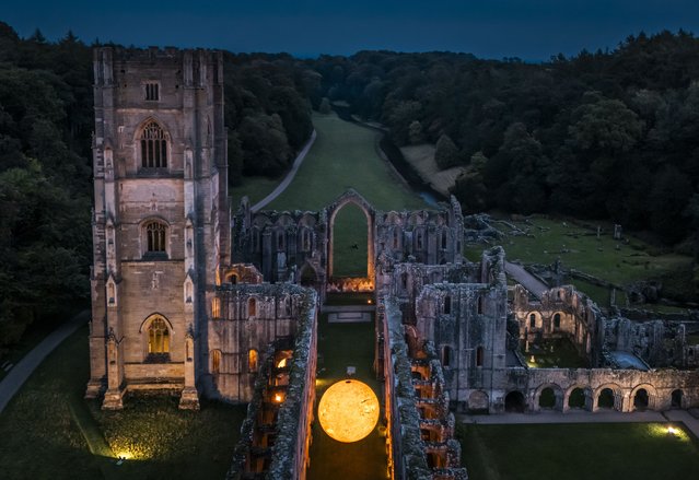 Helios, a seven-metre sun sculpture and soundscape by Luke Jerram, is suspended in the nave of the floodlit abbey ruins of Fountains Abbey, near Aldfield, Ripon in North Yorkshire, UK on Thursday, October 2, 2025. (Photo by Danny Lawson/PA Images via Getty Images)