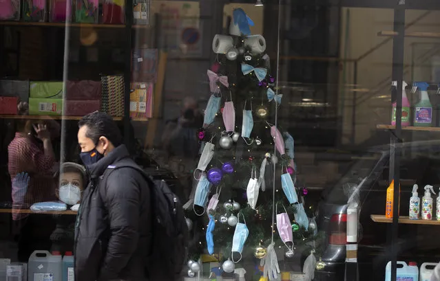 A christmas tree decorated with face masks and toilet rolls is displayed in a store in the street in Madrid, Spain, Thursday, December 17, 2020. Some of Spain's regions are tightening health restrictions for the Christmas holidays with new COVID-19 cases already on the rise again. (Photo by Paul White/AP Photo)