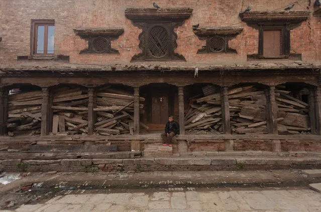 A Nepalese boy sits in front of an earthquake damaged house, half a year after the great earthquake hit the country, in Bhaktapur, Nepal, 25 October 2015. Six months after devastating twin earthquakes struck Nepal, thousands of people are still struggling in temporary shelters and dire conditions. A magnitude-7.8 earthquake on 25 April killed nearly 9,000 people and destroyed hundreds of thousands of houses. (Photo by Hemanta Shrestha/EPA)