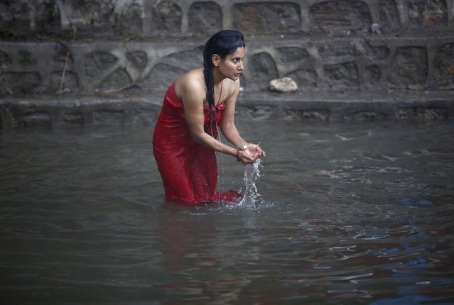 A devotee takes a holy bath in River Saali in Sankhu on the first day of Swasthani Brata Katha festival in Kathmandu January 5, 2015. During the month long festival, devotees recite one chapter of a Hindu tale daily from the 31-chapter sacred Swasthani Brata Katha book that is dedicated to God Madhavnarayan and Goddess Swasthani, alongside various other gods and goddess and the miraculous feats performed by them. (Photo by Navesh Chitrakar/Reuters)