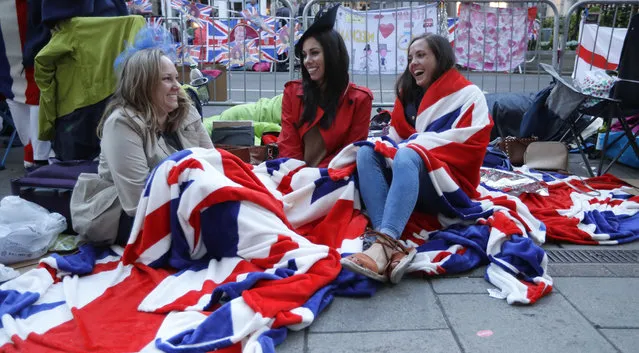 Fans keep warm as they wait to watch the carriage procession after the wedding of Britain's Prince Harry and Meghan Markle at St. George's Chapel in Windsor Castle in Windsor, near London, England, Saturday, May 19, 2018. (Photo by Kirsty Wigglesworth/AP Photo)
