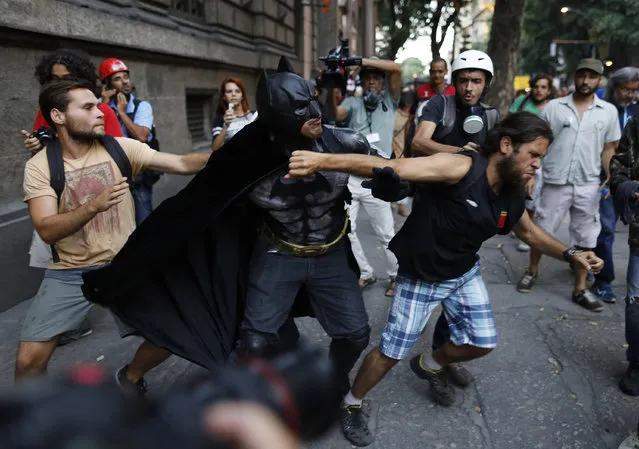 A man wearing a Batman costume reacts after being punched in the face during a protest against the increase in bus fares, in Rio de Janeiro, Brazil, Friday, January 9, 2015. He was attacked after being accused by several demonstrators of having participated in political rallies against the Workers Party during the electoral campaign. (Photo by Leo Correa/AP Photo)