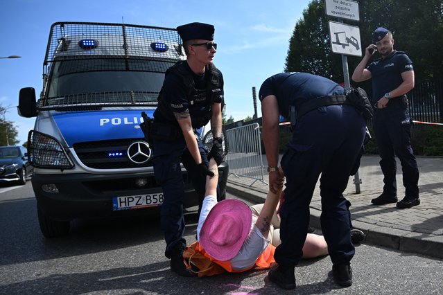 Polish police officers carry away an environmental activist (2ndL) dressed as a fan of US singer Taylor Swift and blocking the entrance to the National Stadium hosting a three-day performance of the pop star in Warsaw, Poland, on August 2, 2024. The activists accuse the US singer of being “detached” from environmental issues. (Photo by Sergei Gapon/AFP Photo)