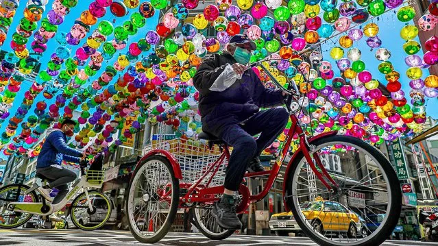 People cycle under colorful lanterns at a tourist attraction area in Changhua, Taiwan, 08 March 2022. On 07 March, Taiwan's Health Minister Chen Shih-chung said that shortening the quarantine period to seven days for arriving passengers to Taiwan by the month of April is a possibility if the COVID-19 situation in Taiwan remains stable and under control. (Photo by Ritchie B. Tongo/EPA/EFE)