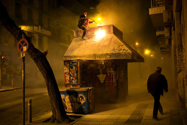 A vendor tries to put out a fire at his kiosk during clashes between riot police and protesters in Athens on December 6, 2015. Anarchists turned part of central Athens into a battleground during a march to mark the seventh anniversary of the fatal shooting of 15-year-old boy by police. Alexis Grigoropoulos was shot dead by police on December 6, 2008 sparking weeks of riots. (Photo by Angelos Tzortzinis/AFP Photo)