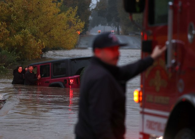 A couple waits for a rescue crew after their car got stuck in deep floodwaters on November 22, 2024 in Windsor, California. A powerful atmospheric river is bringing heavy rains and wind to the San Francisco Bay Area for the third straight day and is expected to rain through the weekend. (Photo by Justin Sullivan/Getty Images)