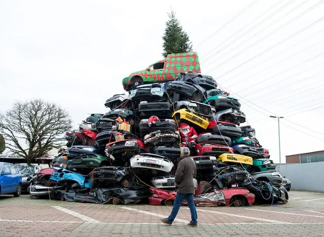 A pile of dozens of junk cars are decorated for Christmas by employees at a car junkyard in Hamburg, Germany, 14 December 2015. (Photo by Daniel Reinhardt/EPA)