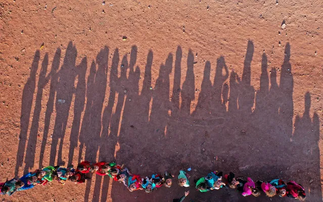 An aerial view taken on October 6, 2020, shows displaced Syrian youths standing in a queue ahead of classes, after tents were transformed to classrooms, at a camp for the internally displaced in the town Maarrat Misrin in Syrias northwestern Idlib province. (Photo by Omar Haj Kadour/AFP Photo)