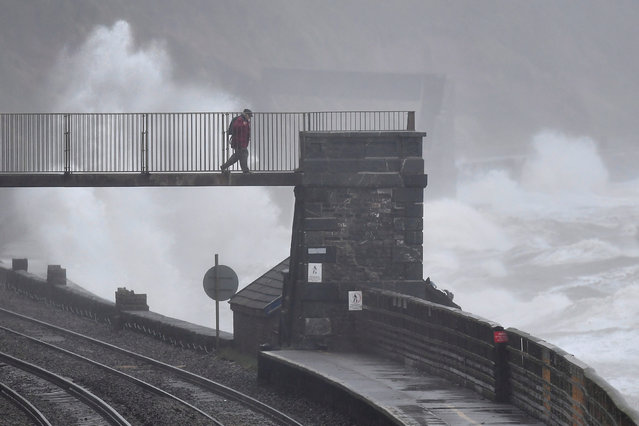 Large waves in strong winds hit the sea wall as a man walks over the railway line at Dawlish in south west Britain, July 29, 2018. (Photo by Toby Melville/Reuters)
