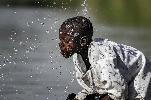 A boy splashes himself with water in the Atbarah river near the village of Dukouli within the Quraysha locality, located in the Fashaqa al-Sughra agricultural region of Sudan's eastern Gedaref state on March 16, 2021. The decades-old border dispute over the Fashaqa fertile farmland region, sandwiched between the Atbarah and Setit (or Tekeze) rivers, and where Ethiopia's northern Amhara and Tigray regions meet Sudan's eastern Gedaref state, dates back decades, feeding regional rivalry and even sparking fears of broader conflict. With the zone contested, the exact area is not clear, but Fashaqa covers some 12,000 square kilometres (4,630 square miles), an area claimed by both Sudan and Ethiopia. (Photo by Ashraf Shazly/AFP Photo)
