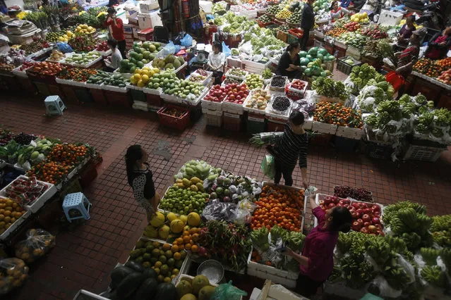 A fruit seller (R, bottom) receives money from a client at a market in Hanoi, Vietnam December 24, 2015. Vietnam saw record low inflation of 0.63 percent in 2015 but the rate could rise to 5 percent next year on anticipated increases in electricity, education and healthcare prices, the government said on Thursday. The inflation average was the lowest since Vietnam started calculating it in 2006, which the General Statistics Office (GSO) attributed to falling oil prices globally. (Photo by Reuters/Kham)