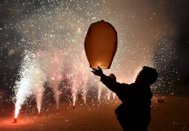 A man releases a paper lantern in front of fireworks ahead of the new year in Hefei, Anhui province, China, December 31, 2015. Picture taken December 31, 2015. (Photo by Reuters/Stringer)