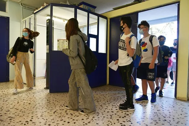 Students wearing face masks to help curb the spread of the coronavirus, wait to check their temperature at a junior high school in Athens, Monday, May 10, 2021. More than 1.1 million pupils and 127,300 teachers returned to school on Monday as primary and junior high school reopened its doors with mandatory home self-tests. (Photo by Michael Varaklas/AP Photo)